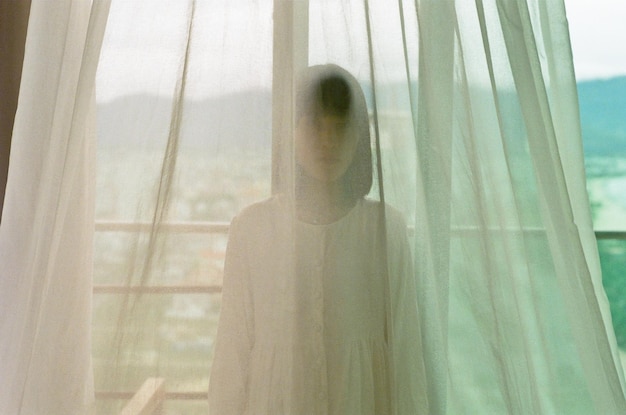 Portrait of young woman behind curtain