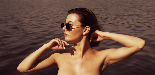 Portrait of a young woman in dark glasses on a background of black water