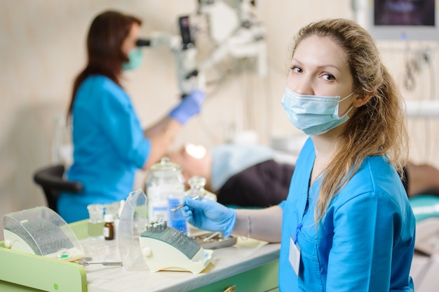 Portrait of young woman dentist assistant holding dental tool