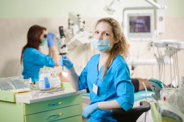 Portrait of young woman dentist assistant holding dental tool