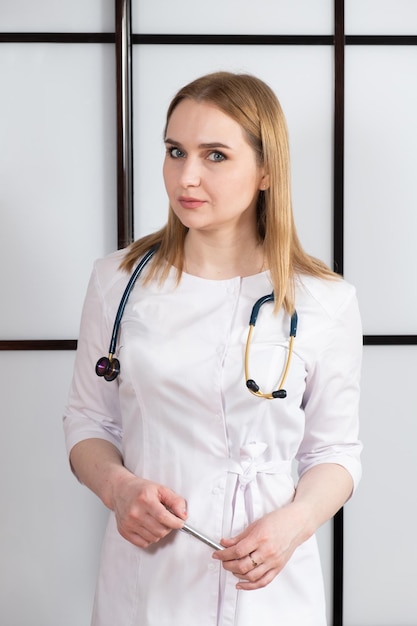 Portrait of a young woman doctor in a white uniform with a stethoscope