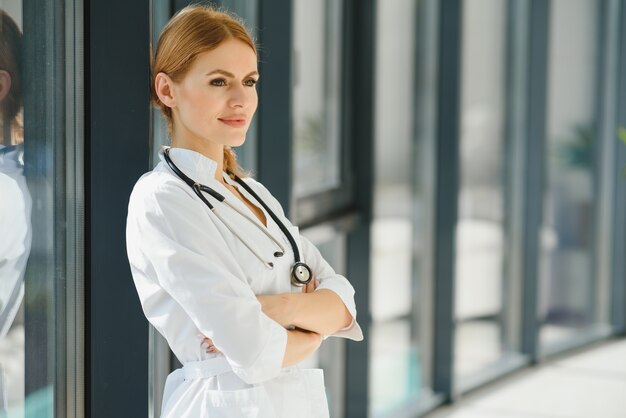 Portrait of young woman doctor with white coat standing in hospital