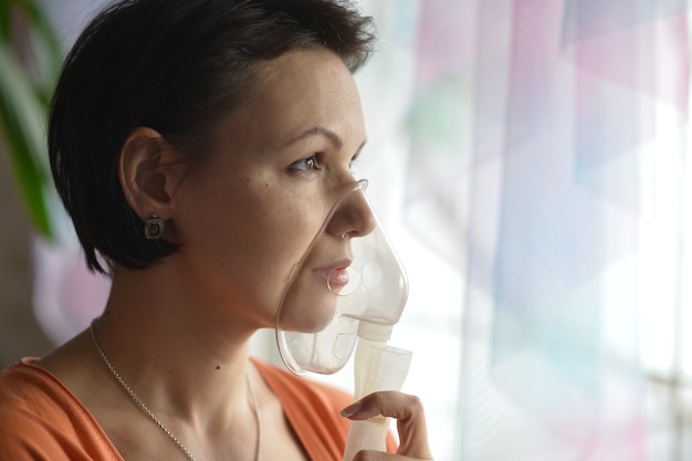 Portrait of a young woman doing inhalation at home