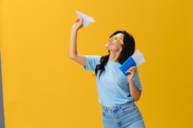 Portrait of young woman drinking bottles against yellow background