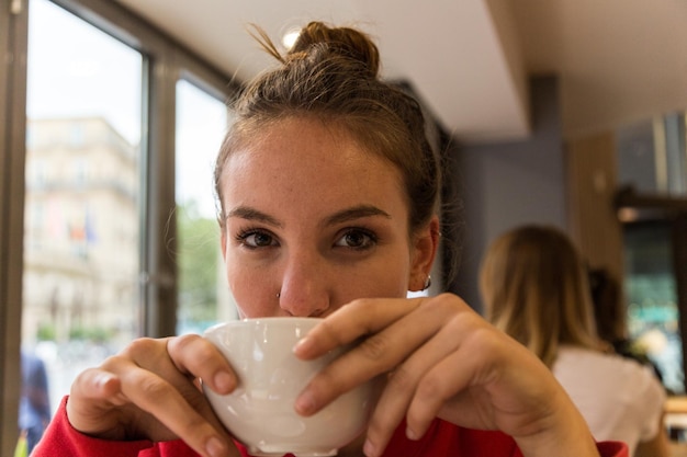 Foto ritratto di una giovane donna che beve caffè in un caffè.