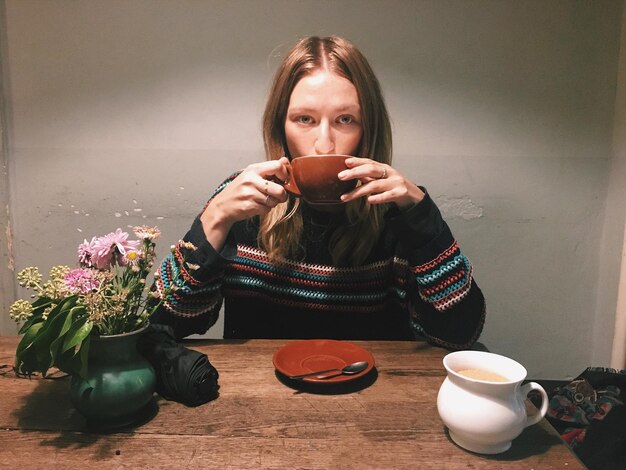 Photo portrait of young woman drinking coffee at table in cafe