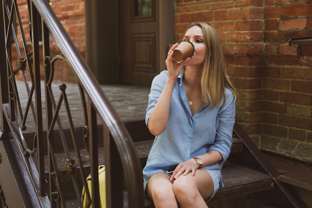 Portrait of a young woman drinks coffee the city street