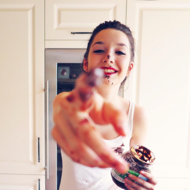 Portrait of young woman eating chocolate from jar