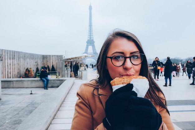 Photo portrait of young woman eating in city