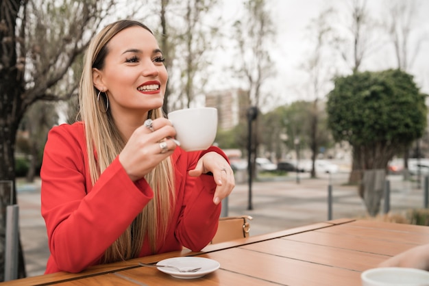 コーヒーショップでコーヒーを楽しんで飲んでいる若い女性の肖像画。ライフスタイルのコンセプト。