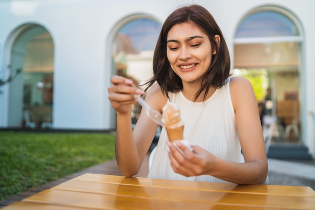 屋外でアイスクリームを食べながら日当たりの良い天気を楽しむ若い女性の肖像画。ライフスタイルのコンセプト。