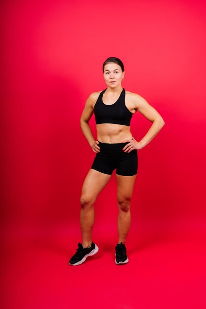 Portrait of young woman exercising against yellow background