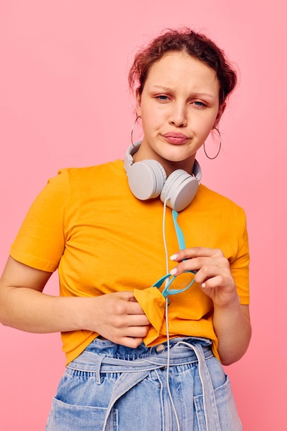 Portrait of a young woman grimace headphones music entertainment technology pink background unaltered