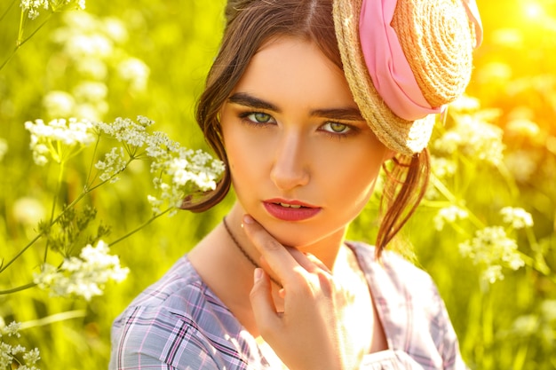 Portrait of a young woman in a hat on the grass