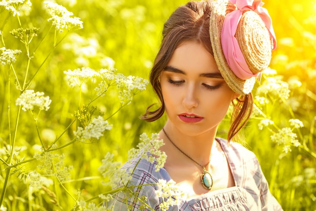 Portrait of a young woman in a hat on the grass