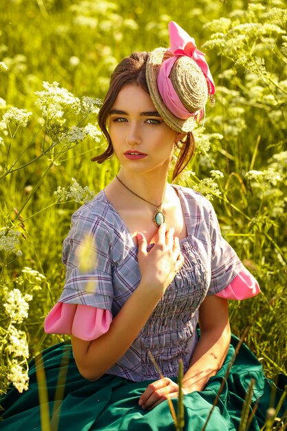 Portrait of a young woman in a hat on the grass