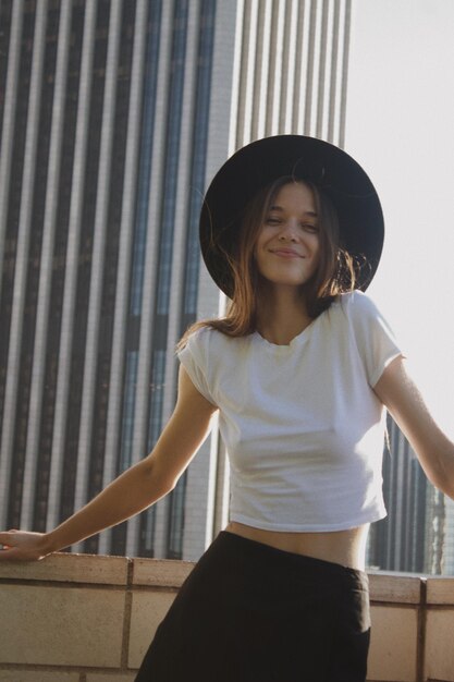 Foto ritratto di una giovane donna con un cappello in piedi contro il muro