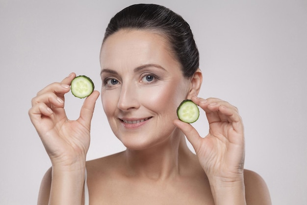 Portrait of young woman holding apple against white background