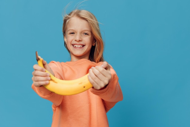 Photo portrait of young woman holding banana against clear blue background