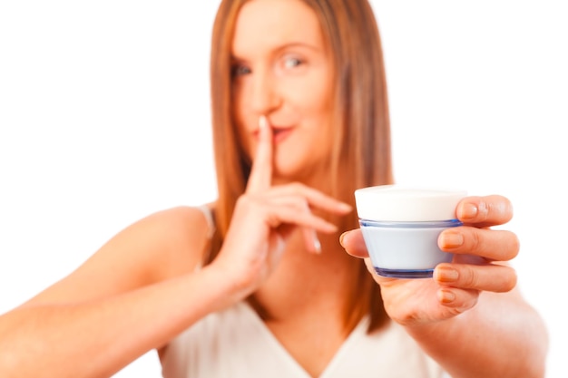 白い背景に美容剤を握っている若い女性の肖像画