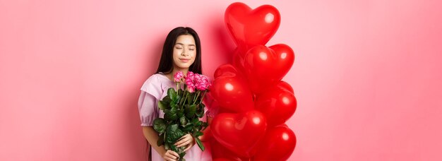 Photo portrait of young woman holding christmas decoration against pink background