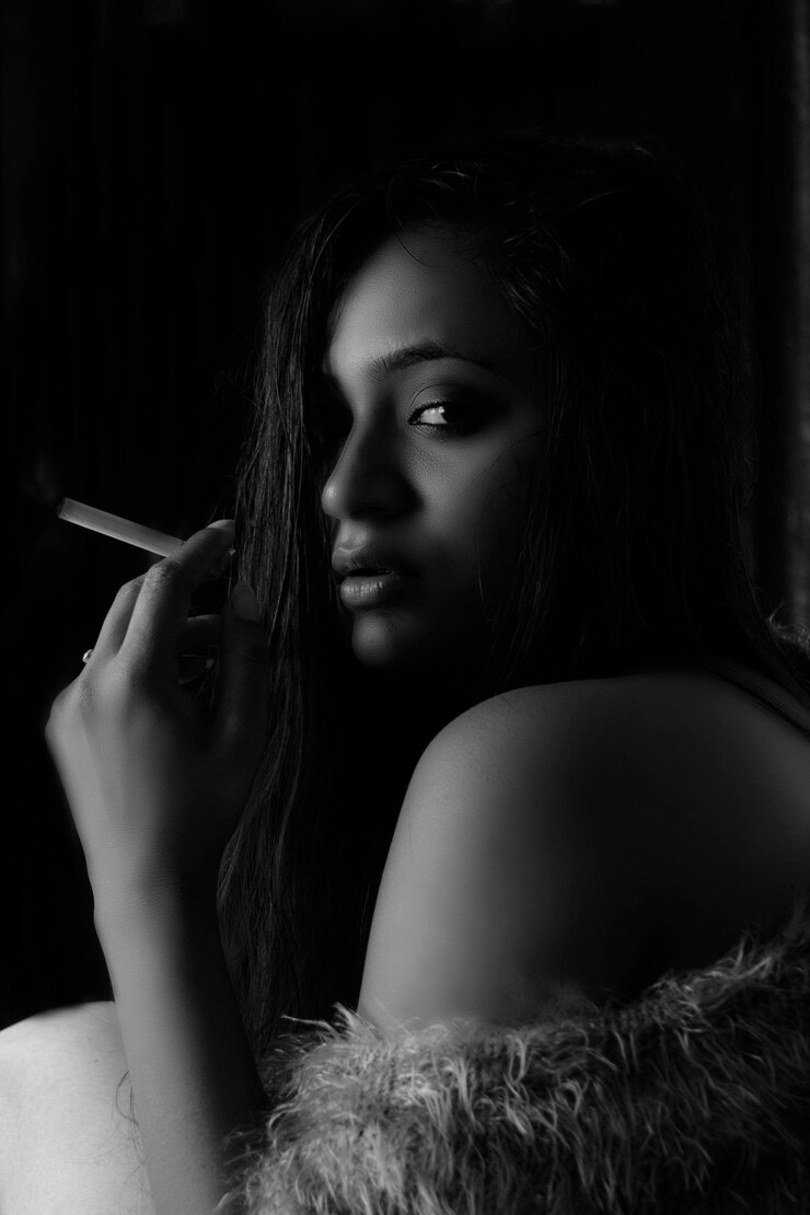 Photo portrait of young woman holding cigarette against black background