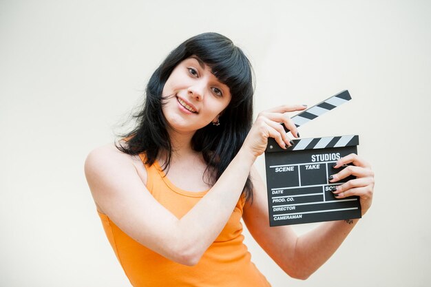 portrait of young woman holding clapperboard over white background
