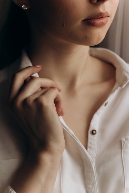 Portrait of young woman, holding collar of white shirt