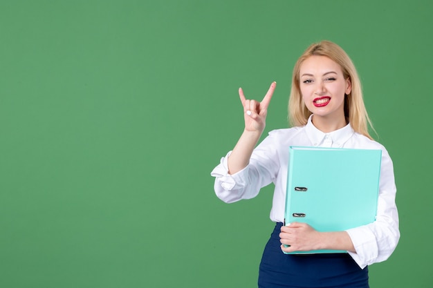 portrait of young woman holding document green wall teacher student lesson