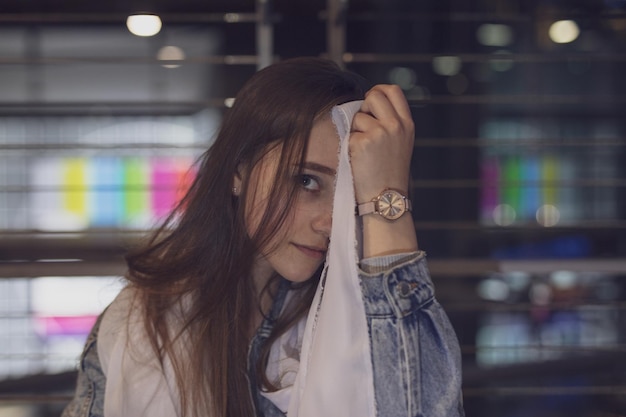 Photo portrait of young woman holding fabric against metal fence