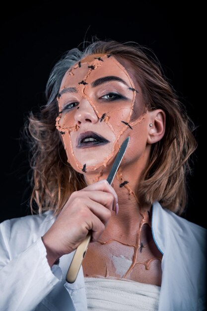 Portrait of young woman holding face against black background