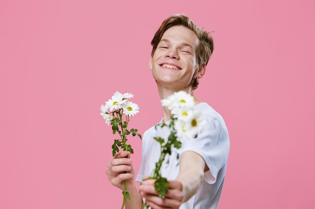 Foto ritratto di una giovane donna con dei fiori sullo sfondo rosa