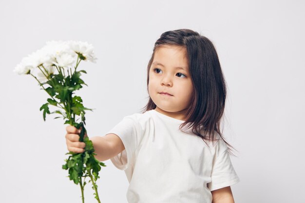 白い背景に花を掲げている若い女性の肖像画