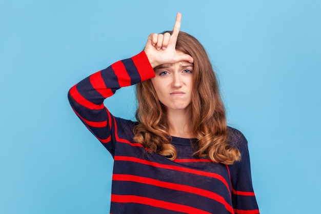 Portrait of young woman holding gift against blue background