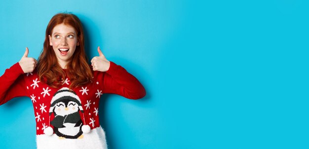 Portrait of young woman holding gift against blue background