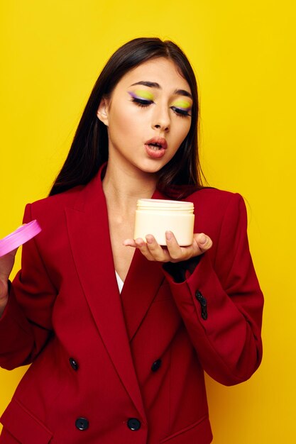 Portrait of young woman holding gift against yellow background