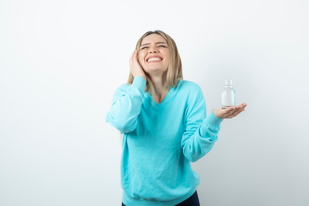 Portrait of young woman holding glass pitcher of water in hand