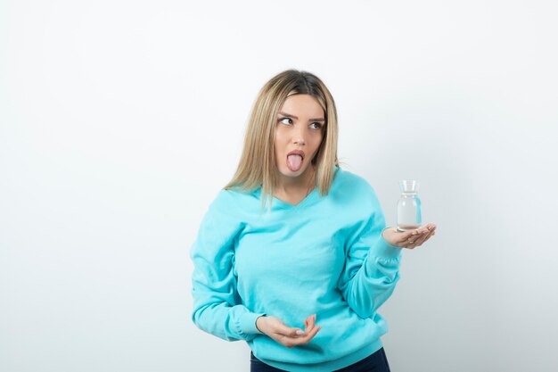 Portrait of young woman holding glass pitcher of water in hand