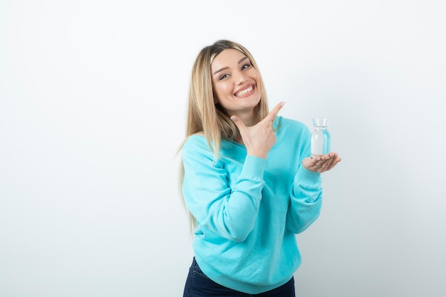 Portrait of young woman holding glass pitcher of water in hand