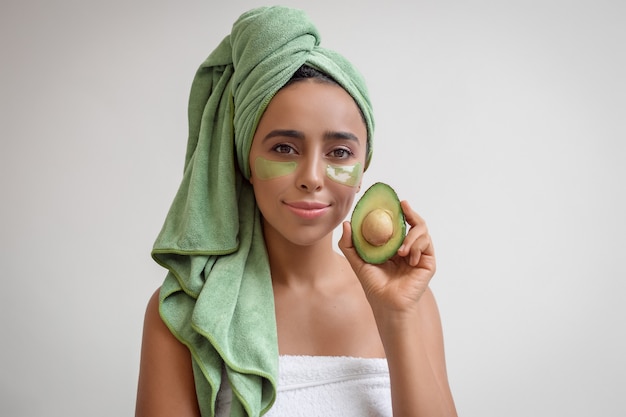 Portrait of a young woman holding a half avocado in her hand