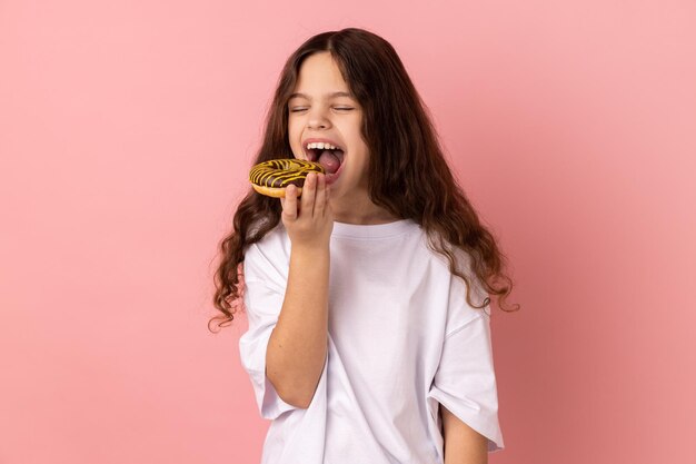 Portrait of young woman holding ice cream cone against pink background