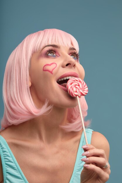 Photo portrait of young woman holding lollipop against black background