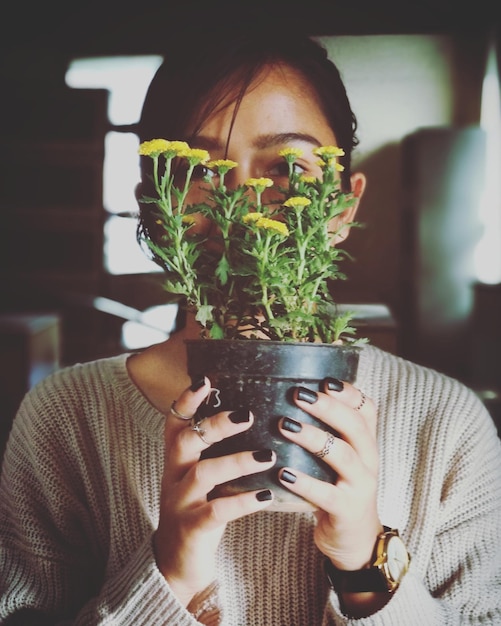 Photo portrait of young woman holding potted plant