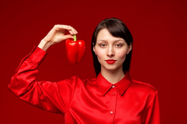 Foto ritratto di giovane donna che tiene peperone rosso