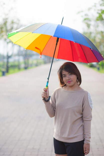 Portrait of young woman holding umbrella while standing on road