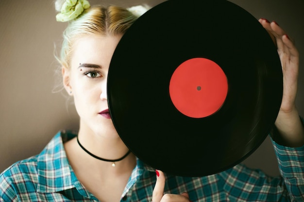 Foto ritratto di una giovane donna con un disco in vinile in piedi a casa