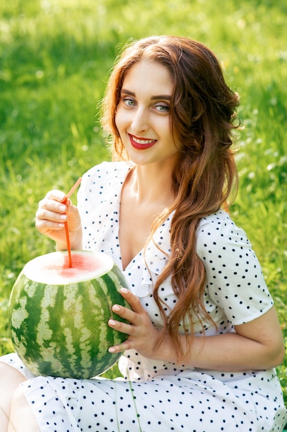 Portrait of young woman holding a whole watermelon.