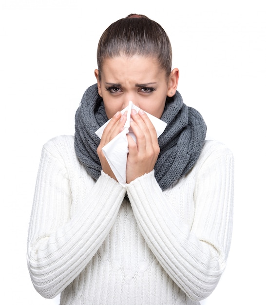 Portrait of a young woman is blowing nose.