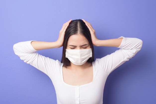 Portrait of young woman is wearing face mask on purple background