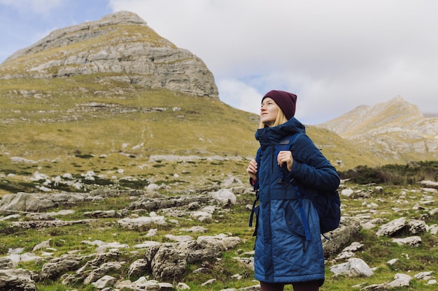 Ritratto di una giovane donna in giacca e con uno zaino sullo sfondo delle montagne turista femminile durante le escursioni